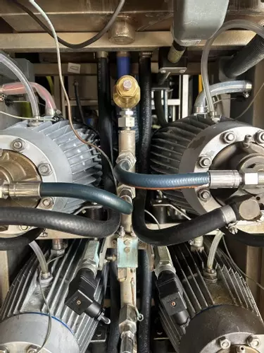 Corroded capillary pipes connected to the pressure manifold on a Nilfisk Delta Booster multi-pump pressure washer before replacement.